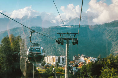 Overhead cable car over mountains against sky