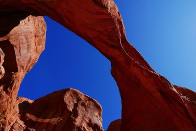 Low angle view of rock formation against clear blue sky