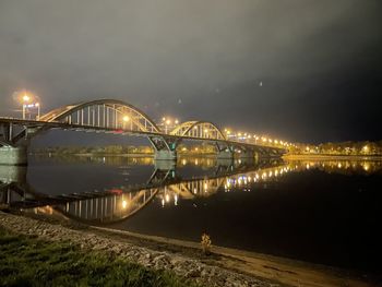 Illuminated bridge over river against sky at night