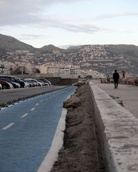 Rear view of people walking on road against sky