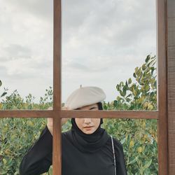 Portrait of young woman standing by railing