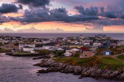 Townscape by sea against sky during sunset