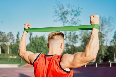 Midsection of man with arms raised against sky