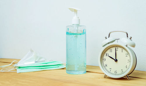 Close-up of clock on glass table against wall