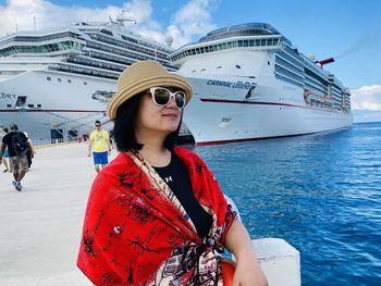 Young woman wearing sunglasses against boat in sea against sky