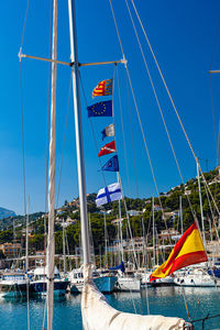 Sailboats moored in sea against blue sky