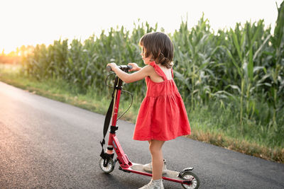 Girl in red dress riding red scooter