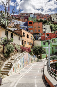Road by buildings in city against sky