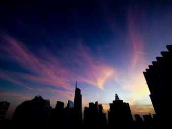 Low angle view of buildings against cloudy sky during sunset