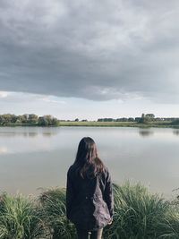Rear view of woman looking at lake against sky