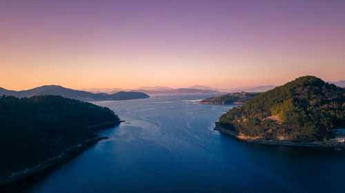 Scenic view of river by mountains against clear sky