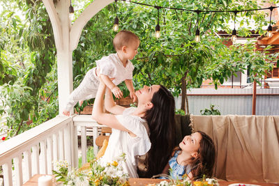 Mother and girl smiling while standing against plants