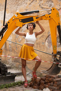 Full length of woman standing by construction vehicle