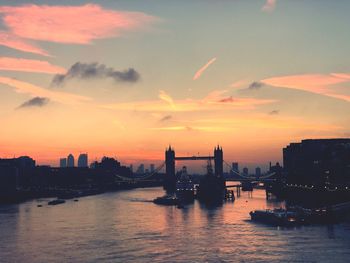 Scenic view of river by buildings against sky during sunset