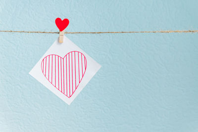 Close-up of heart shape decoration hanging against white wall