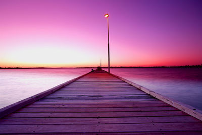 Pier over sea against sky during sunset