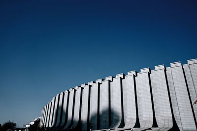 Low angle view of factory against clear blue sky