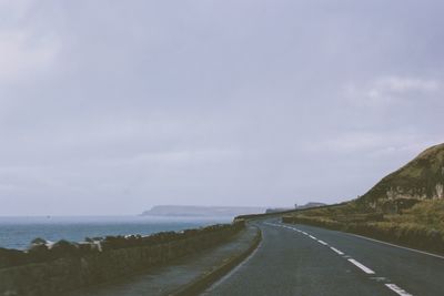 Empty road by mountain against sky