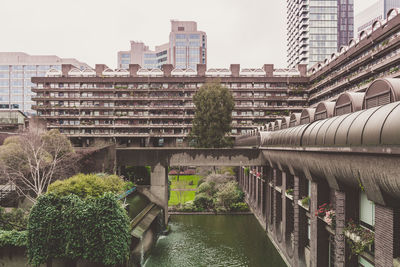 Bridge over river by buildings in city against sky