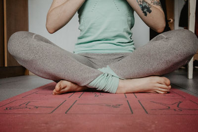 Low section of woman exercising yoga at home