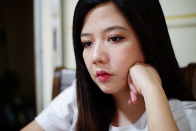 Young woman looking away while sitting at home