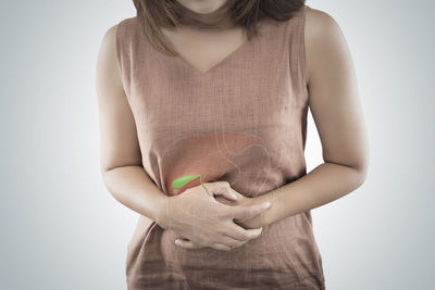 Midsection of woman standing against white background