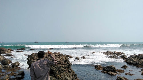 Rear view of rocks on beach against sky