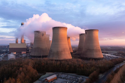 Aerial view of coal fired power station chimneys and cooling towers polluting atmosphere at sunset