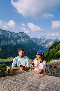 People sitting on table by mountains against sky