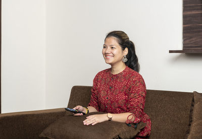 Portrait of a smiling young woman sitting on sofa