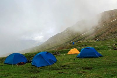 Scenic view of tent on mountain against cloudy sky