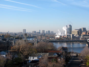 Bridge over river in city against sky