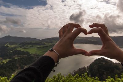 Close-up of hands against sky