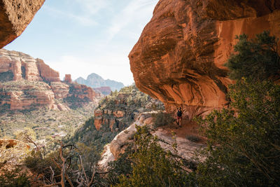 30s female stands on cliff enjoying views of boynton canyon in sedona.