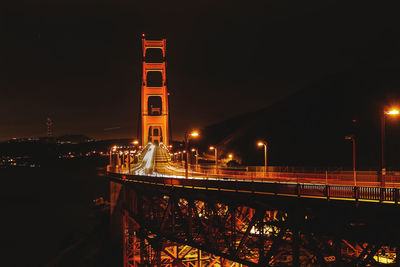 Illuminated bridge against clear sky at night