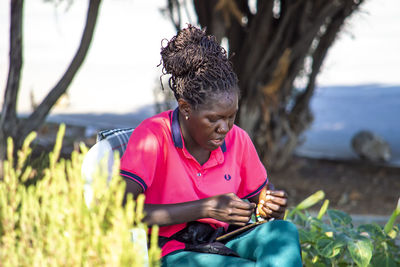 Woman looking at camera while sitting on land