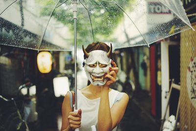 Woman with umbrella covering face with mask outdoors