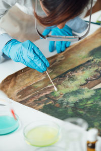 Oil painting cleaning, female conservator removing dirt from an old oil painting