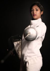 Portrait of woman standing against black background