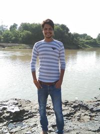 Portrait of young man standing against lake