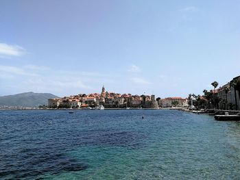 Buildings by sea against blue sky