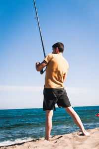 Rear view of man on beach against sky