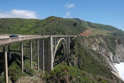 Arch bridge over mountains against sky