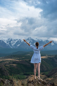 Rear view of man standing on mountain against sky