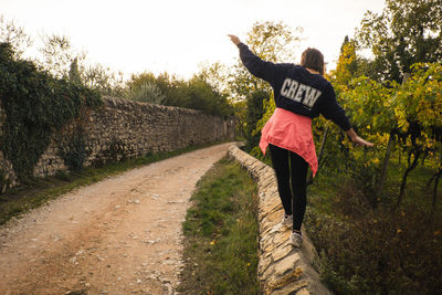 Rear view of woman walking on road amidst trees