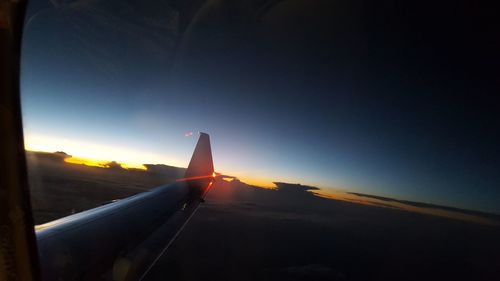 Close-up of airplane wing against sky during sunset