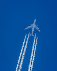 A freighter airplane works its way slightly across the sky leaving 4 temporary contrails