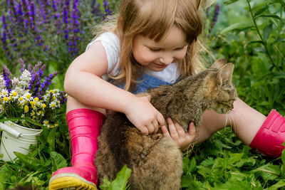 Cute girl with cat sitting amidst plants