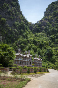 Built structure by trees on mountain against sky