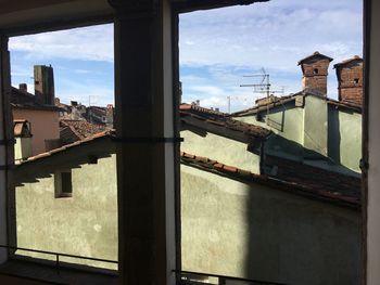 Buildings against sky seen through train window